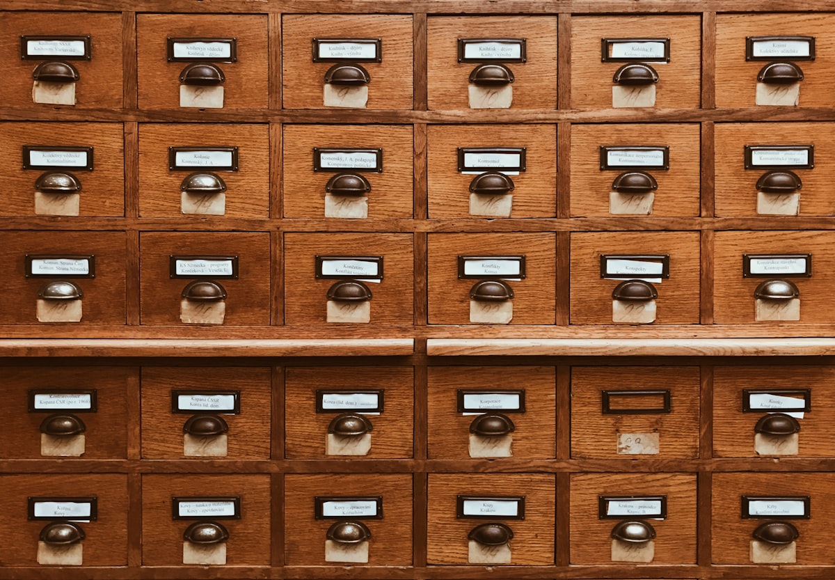 Vintage library card catalog with labeled wooden drawers in warm lighting