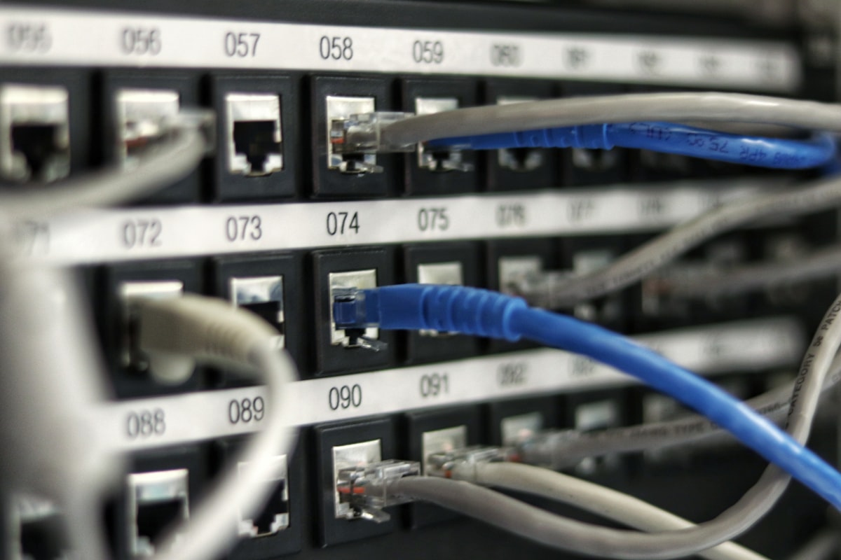 Network patch panel with numbered RJ45 ports and colored ethernet cables plugged in